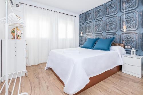科尔多瓦BHost - Tendillas的卧室配有带蓝色枕头的大型白色床
