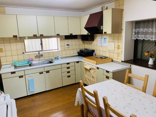 千叶homelike / Vacation STAY 33817的厨房配有白色橱柜、桌子和水槽。