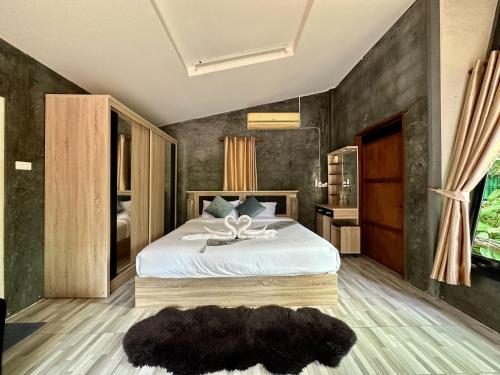 湄登Rai Phusaitran ไร่ภูสายธาร的一间卧室设有一张大床和黑色墙壁