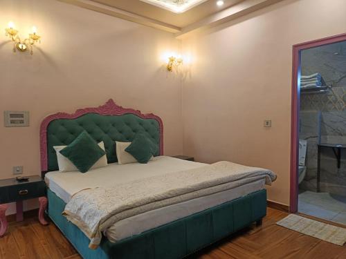 阿格拉玛雅酒店及餐厅的一间卧室配有一张大床和绿色床头板