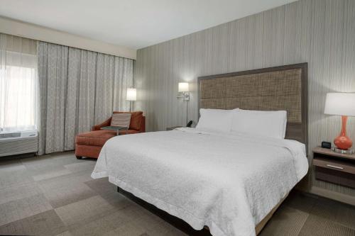科林斯维尔圣路易斯/科林斯维尔希尔顿恒庭酒店的酒店客房带一张大床和一把椅子