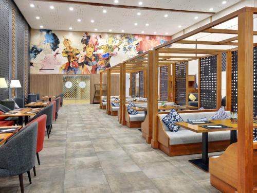 库塔巴厘岛国际机场诺富特酒店的一间带桌椅和壁画的餐厅