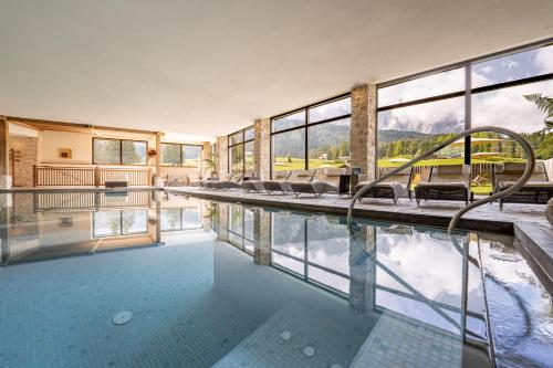 圣克里斯蒂娜Monte Pana Dolomites Hotel的房屋设有游泳池、椅子和窗户