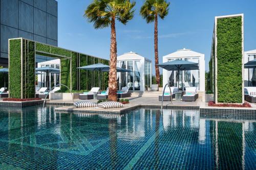 科威特Waldorf Astoria Kuwait的一座棕榈树和遮阳伞的游泳池