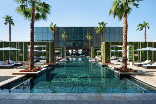 科威特Waldorf Astoria Kuwait的一座楼前种有棕榈树的游泳池