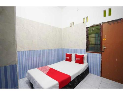 泗水OYO Life 93061 Kost Vicky Syariah的一间卧室配有一张带两个红色枕头的床