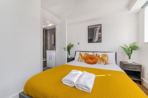 伦敦Luxury 2 Bed 2 Bath London Home - Vauxhall, Battersea & Nine Elms的一间卧室配有黄色的床和毛巾