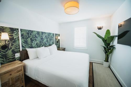 新奥尔良Marsh Hotel的卧室配有白色的床和盆栽植物