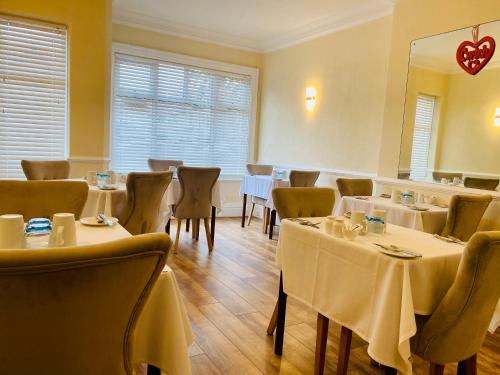 兰迪德诺Cwtch Guesthouse的餐厅配有桌椅和白色桌布