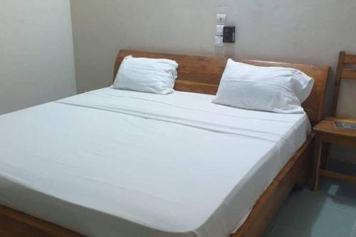 OuidahOuidah Lodge的一张带白色床单和枕头的床