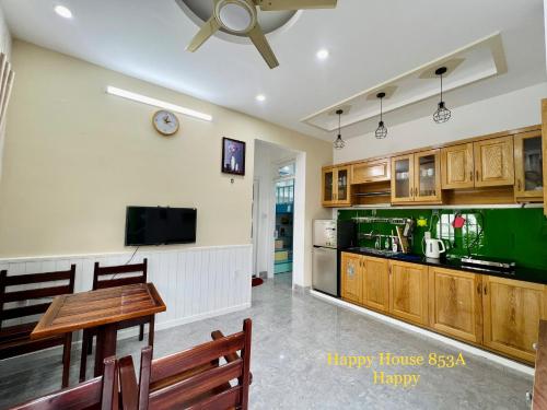 头顿Căn Happy的一间带桌子和电视的客厅以及一间厨房。
