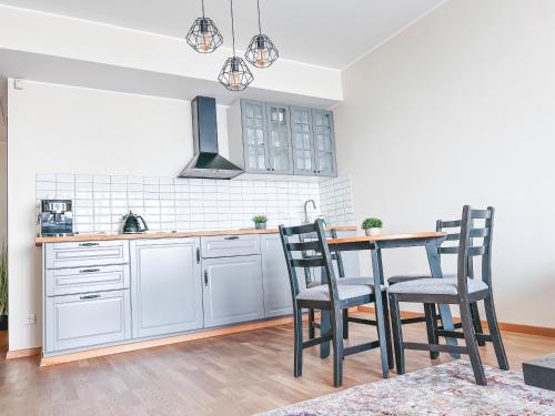 克莱佩达UP 34 FLOOR APARTMENTS的厨房配有白色橱柜和一张带椅子的木桌