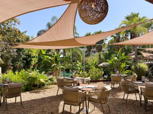 戛纳戛纳圣巴特别墅酒店的一个带桌椅和遮阳伞的户外庭院。