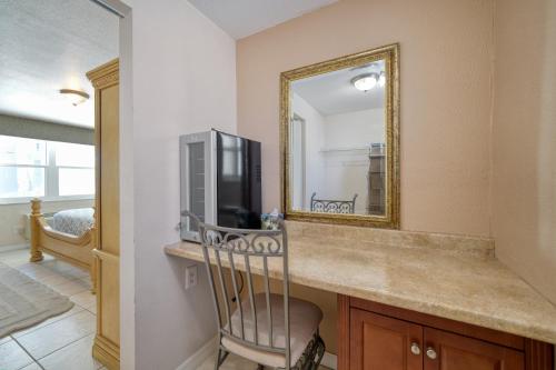 克利尔沃特卡米洛特海滩套房酒店的一间带镜子的台面和电视的浴室