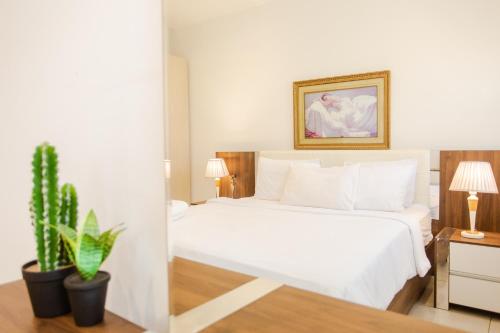 CantonmentsAccra Luxury Apartments @ Pine Court的卧室配有白色的床和盆栽植物