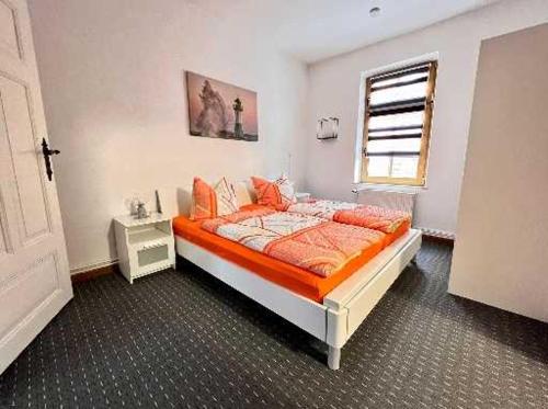 萨斯尼茨Ferienwohnungen Otto的一间卧室配有带橙色床单的床和窗户。