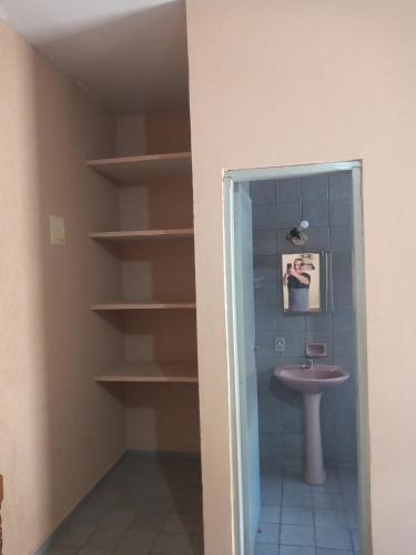 乌贝拉巴Kitnets para temporada的一间带水槽、卫生间和书架的浴室