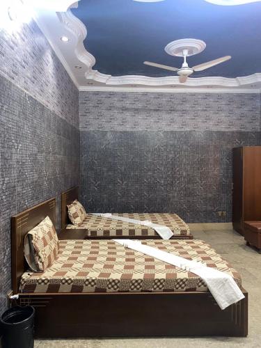 卡拉奇Jinnah inn Guest House的一间卧室配有两张床和吊扇