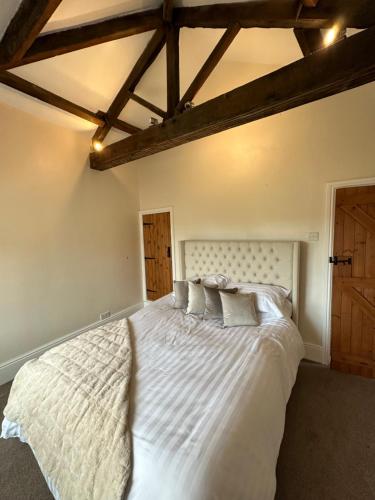 ConisbroughSugar Plum Cottage的卧室配有一张白色大床和木制天花板