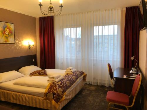 柏林Atlas Berlin Hotel的配有一张床、一张书桌和一扇窗户的酒店客房