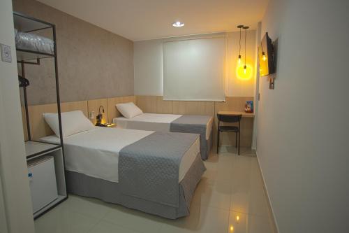 CianorteGoldmen Hotel Express的酒店客房配有两张床和一张书桌