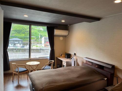 日田市Ryokan Tenryu的一间卧室配有一张床、一张书桌和一个窗户。