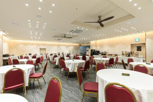 西归浦市Hotel The Grang Seogwipo的宴会厅配有白色桌子和红色椅子