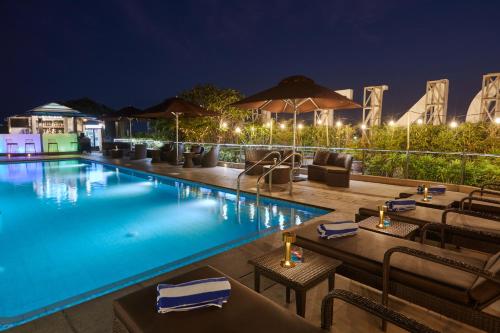 马尼拉Belmont Hotel Manila的夜间酒店带桌椅的游泳池