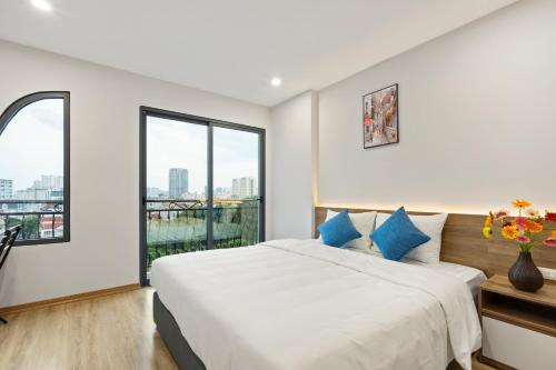 河内22housing Residence Suites的白色卧室配有一张带蓝色枕头的大床