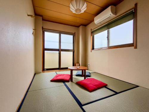 东京Ostay Numabukuro Hotel Apartment的一间房间,配有一张桌子和两个红色垫子