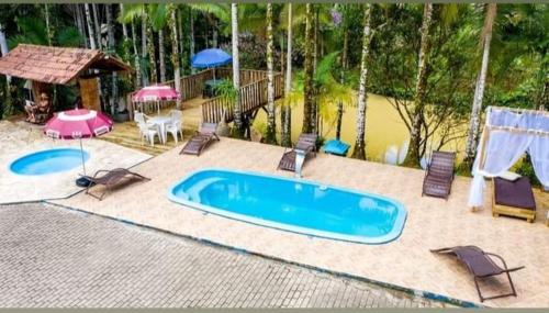GuabirubaSuíte alvenaria casal.的后院的游泳池,配有椅子和遮阳伞