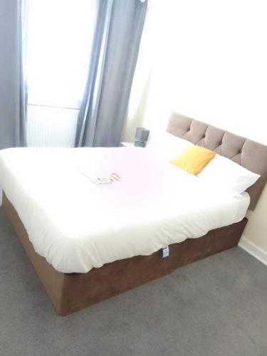 InvergowrieMide’s House的一张带白色床单和黄色枕头的床
