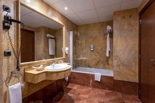 蓬费拉达埃洛伊比耶索广场酒店的一间带水槽、浴缸和镜子的浴室