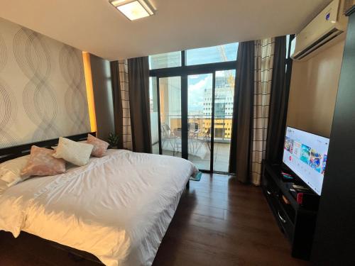 宿务Appleone Ayala Condo with Balcony的一间卧室配有一张床和一台平面电视