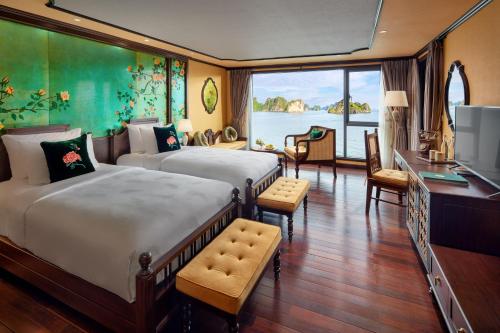 下龙湾Indochine Premium Halong Bay Powered by Aston的一间卧室配有两张床、一张桌子和一台电视。