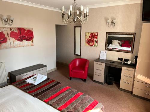 绍斯波特Southport Metro Hotel的一间卧室配有一张床、一张桌子和一把红色椅子