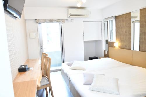 东京日本桥阿克萨斯公寓式酒店的小房间设有两张床、一张桌子和窗户
