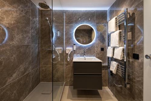 蒙绍ACHAT Hotel Monschau的带淋浴、盥洗盆和镜子的浴室