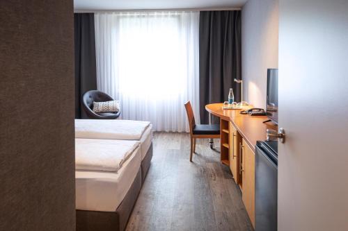 蒙绍ACHAT Hotel Monschau的配有一张床和一张书桌的酒店客房