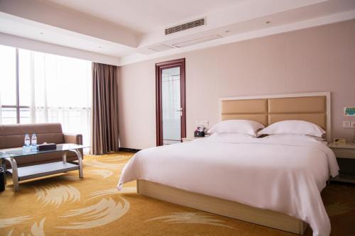 铜仁铜仁世纪大酒店的卧室配有一张白色的大床和一张沙发。