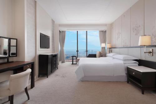 青岛青岛李沧绿城喜来登酒店 的一间卧室配有一张床、一张书桌和一台电视