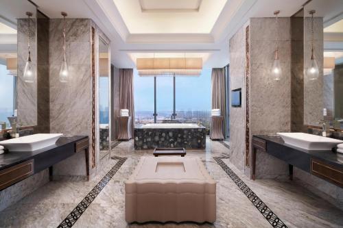 青岛青岛李沧绿城喜来登酒店 的浴室配有两个盥洗盆和浴缸。