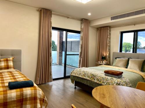 悉尼Penshurst Guest House的一间带两张床和一张桌子的卧室以及一个阳台