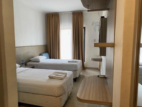 SukaramiBelvena Makati Hotel的酒店客房设有两张床和一张桌子。