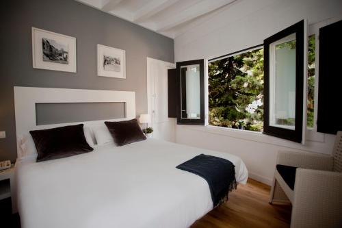 锡切斯Hotel Sitges Rooms的卧室配有白色的床和2扇窗户。