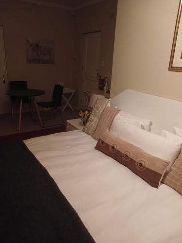 开普敦Greenbank Cottage的一张大白色的床,位于带桌子的房间