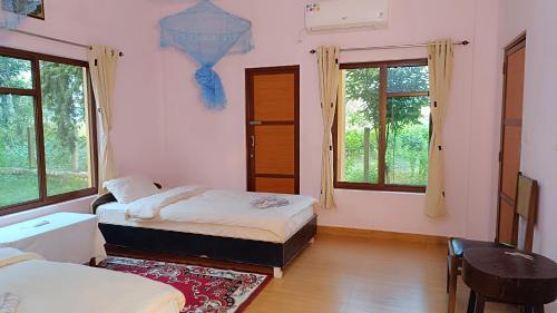 BhurkīāMr. B's Place的一间卧室设有两张床、一张桌子和窗户。