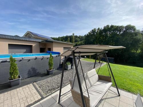 LandscheidEifel-Mosel-Hideaway的游泳池旁的天井配有椅子和遮阳伞