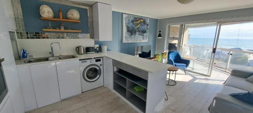 布鲁堡史特兰201 Coral Island, 88 Coral Road, Bloubergstrand的厨房配有水槽和洗衣机