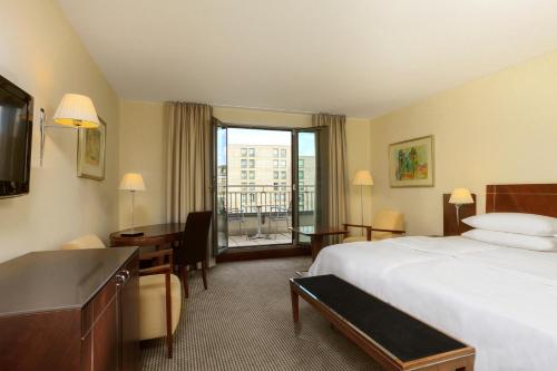纽伦堡纽伦堡喜来登酒店的配有一张床和一张书桌的酒店客房